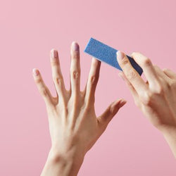 Limage manuel d’ongles naturels avec un bloc polissoir 4 faces bleu sur fond rose